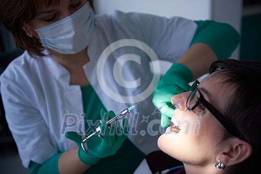 Closeup of a woman patient at the dentist waiting to be checked up with the woman doctor in the background Closeup of a woman patient at the dentist waiting to be checked up with the woman doctor in the background
