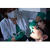 Closeup of a woman patient at the dentist waiting to be checked up with the woman doctor in the background