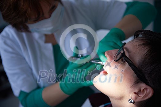 Closeup of a woman patient at the dentist waiting to be checked up with the woman doctor in the background Closeup of a woman patient at the dentist waiting to be checked up with the woman doctor in the background