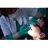 Closeup of a woman patient at the dentist waiting to be checked up with the woman doctor in the background