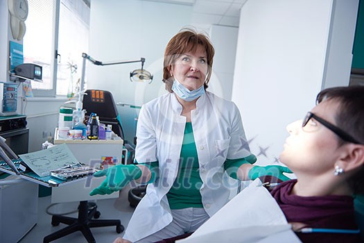 Closeup of a woman patient at the dentist waiting to be checked up with the woman doctor in the background Closeup of a woman patient at the dentist waiting to be checked up with the woman doctor in the background