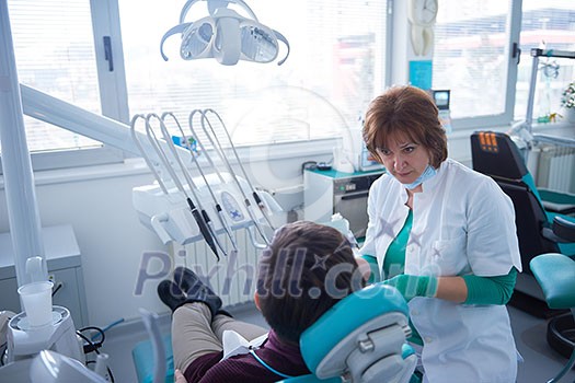 Closeup of a woman patient at the dentist waiting to be checked up with the woman doctor in the background Closeup of a woman patient at the dentist waiting to be checked up with the woman doctor in the background