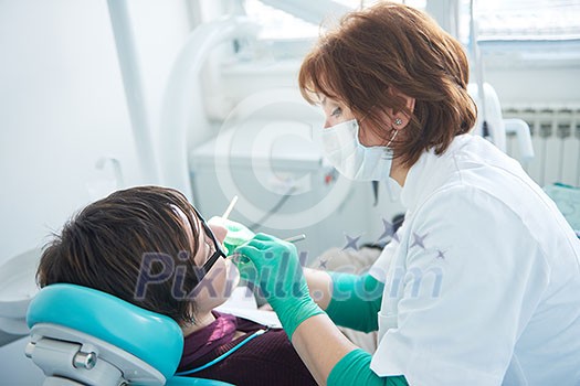 Closeup of a woman patient at the dentist waiting to be checked up with the woman doctor in the background Closeup of a woman patient at the dentist waiting to be checked up with the woman doctor in the background