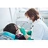 Closeup of a woman patient at the dentist waiting to be checked up with the woman doctor in the background