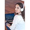 beautiful young woman relax and work on laptop computer modern  home office while listening musin on white headphones
