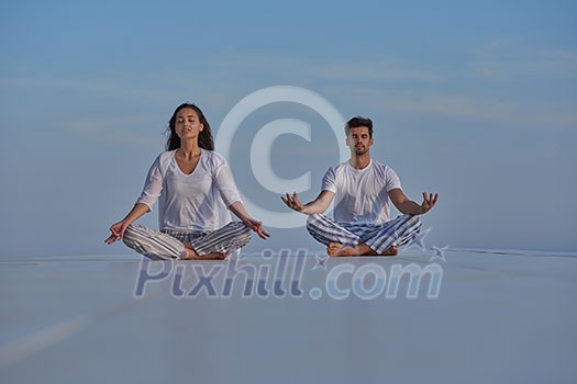 young couple practicing yoga at sunset in modern home terace with ocean and sunset in background young couple practicing yoga at sunset in modern home terace with ocean and sunset in background