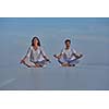 young couple practicing yoga at sunset in modern home terace with ocean and sunset in background