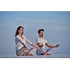 young couple practicing yoga at sunset in modern home terace with ocean and sunset in background