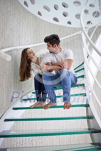 relaxed young couple on spiral glass stairs in modern home villa indoors relaxed young couple on spiral glass stairs in modern home villa indoors