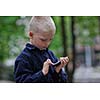 young blonde boy playing videogames outdoor in park