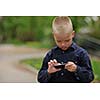 young blonde boy playing videogames outdoor in park