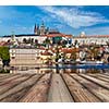 Wooden planks vith view of Prague Charles bridge over Vltava river and Gradchany (Prague Castle) and St. Vitus Cathedral in background