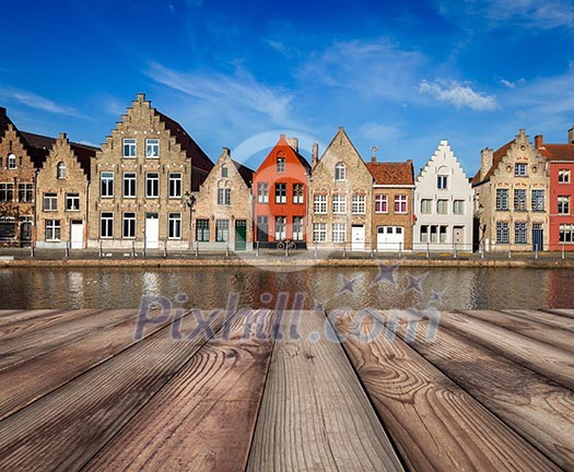 Wooden planks table with typical European Europe cityscape view - canal and medieval houses in background. Brugge, Belgium Wooden planks table with typical European Europe cityscape view - canal and medieval houses in background. Brugge, Belgium