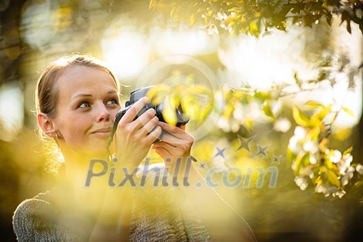Pretty female amateur photographer taking photos outdoors, doing what she loves to do Pretty female amateur photographer taking photos outdoors, doing what she loves to do