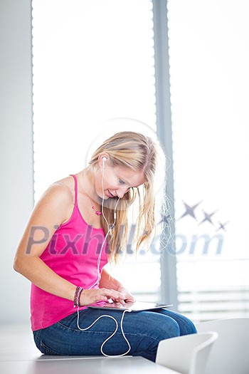 Pretty, young female student listening to music on her tablet computer (color toned image) Pretty, young female student listening to music on her tablet computer (color toned image)