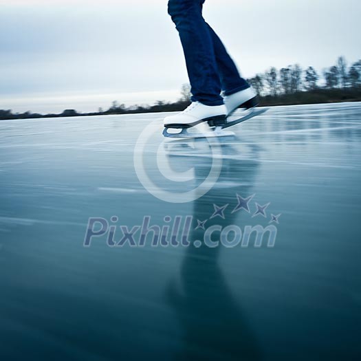 Young woman ice skating outdoors on a pond on a freezing winter day Young woman ice skating outdoors on a pond on a freezing winter day