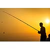 Fisherman silhouette on the beach at colorful sunset
