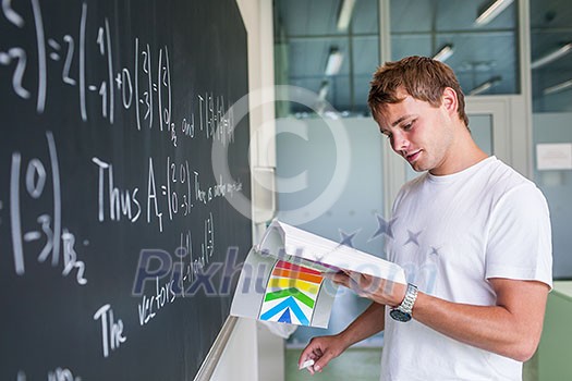 Handsome college student solving a math problem during math class in front of the blackboard/chalkboard (color toned image) Handsome college student solving a math problem during math class in front of the blackboard/chalkboard (color toned image)