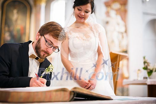 Groom signing the Contract of his life - Portrait of a young wedding couple on their wedding day Groom signing the Contract of his life - Portrait of a young wedding couple on their wedding day