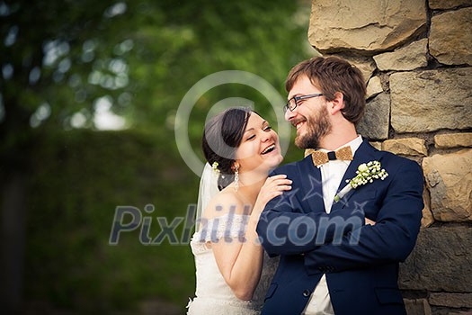 Portrait of a young wedding couple on their wedding day, looking happy, laughing together instead of posing properly for the photographer Portrait of a young wedding couple on their wedding day, looking happy, laughing together instead of posing properly for the photographer