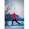 Young woman running outdoors on a cold winter day (motion blurred image)