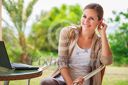 Portrait of a pretty young woman working on her computer on a terrace of her house Portrait of a pretty young woman working on her computer on a terrace of her house