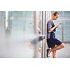 Portrait of a sleek young woman calling on a smartphone and using her laptop in a an
urban/city context (shallow DOF; color toned image)