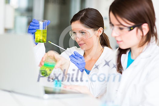 Two young female researchers carrying out experiments in a lab (shallow DOF; color toned image) Two young female researchers carrying out experiments in a lab (shallow DOF; color toned image)