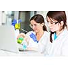 Two young female researchers carrying out experiments in a lab (shallow DOF; color toned image)