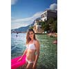 Pretty, young woman enjoying a day at the beach, relaxing on inflatable mattress