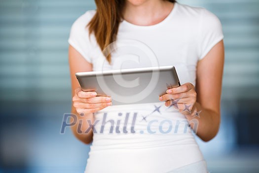 Pretty, young businesswoman/colle ge student using her tablet computer (shallow DOF; color toned image)