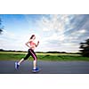 Young woman running outdoors on a lovely sunny winter/fall day (motion blurred image)