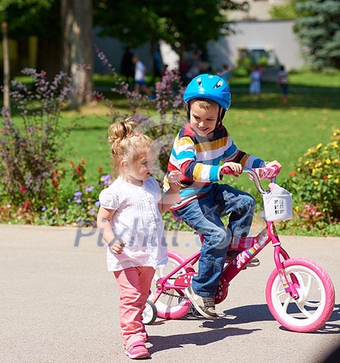 Happy childrens outdoor, brother and sister in park have fun. Boy and girl in park learning to ride a bike. Happy childrens outdoor, brother and sister in park have fun. Boy and girl in park learning to ride a bike.
