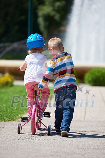 Happy childrens outdoor, brother and sister in park have fun. Boy and girl in park learning to ride a bike. Happy childrens outdoor, brother and sister in park have fun. Boy and girl in park learning to ride a bike.