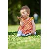 happy young baby child sittng on grass on beautiful summer day in park