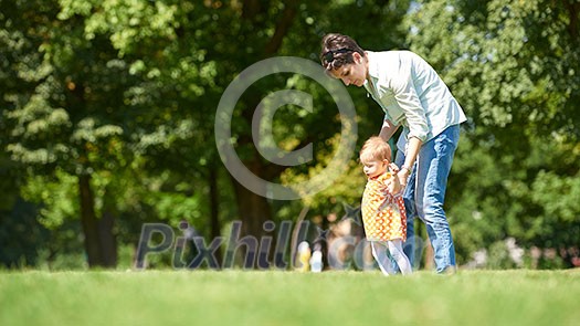 happy mother and baby child in park making first steps . Walking and hugging. happy mother and baby child in park making first steps . Walking and hugging.