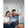 happy young relaxed  couple working on laptop computer at modern home indoor