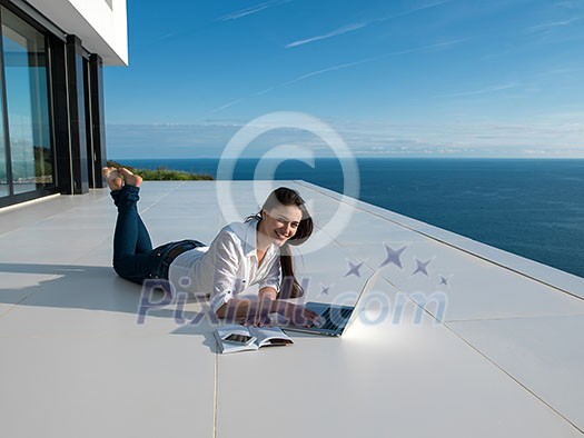 beautiful young woman relax and work on laptop computer and read book at modern home beautiful young woman relax and work on laptop computer and read book at modern home
