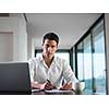 portrait of young happy business man working on laptop computer at home