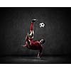 Football player kicking ball against dark background