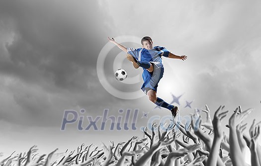 Football player in jump kicking the ball supported by fans Football player in jump kicking the ball supported by fans