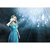 Young blond girl in blue dress listening music