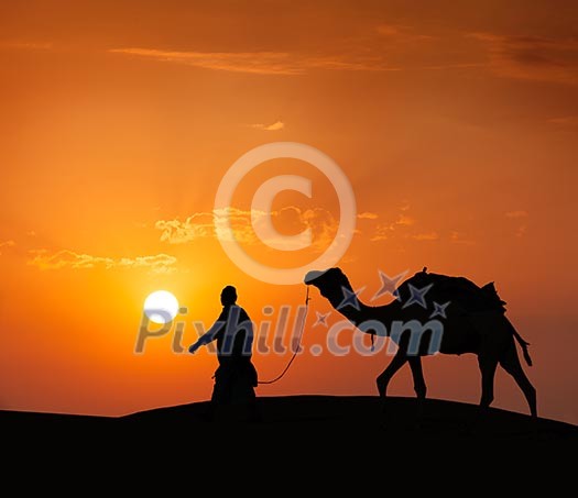Rajasthan travel background - indian cameleer (camel driver) with camel silhouette in dunes of Thar desert on sunset. Jaisalmer, Rajasthan, India Rajasthan travel background - indian cameleer (camel driver) with camel silhouette in dunes of Thar desert on sunset. Jaisalmer, Rajasthan, India