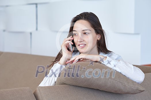 happy young woman using cellphone at home and relaxing happy young woman using cellphone at home and relaxing
