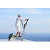 healthy senior man working out on gym treadmill machine at modern home terace with ocean view