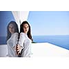 relaxed young beautiful woman in front of luxury modern home villa  on balcony on sunny day