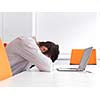 Frustrated young business man have stress problems. Sitting alone at office meeting room  and working on laptop compute.