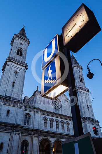 U-Bahn sign and St. Ludwig's Church (Ludwigskirche) in the evening. Car Light Traces motion blur because of long exposure. Munich, Bavaria, Germany U-Bahn sign and St. Ludwig's Church (Ludwigskirche) in the evening. Car Light Traces motion blur because of long exposure. Munich, Bavaria, Germany