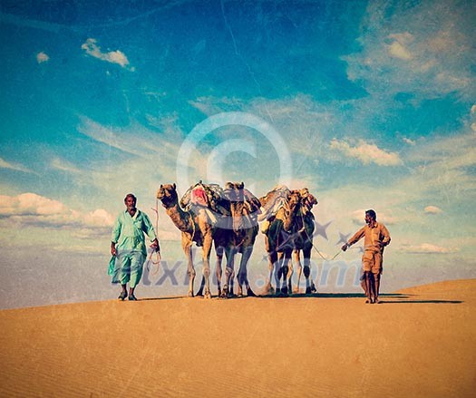 Vintage retro hipster style travel image of Rajasthan travel background - two Indian cameleers (camel drivers) with camels in dunes of Thar desert. Jaisalmer, Rajasthan, India with grunge texture overlaid Vintage retro hipster style travel image of Rajasthan travel background - two Indian cameleers (camel drivers) with camels in dunes of Thar desert. Jaisalmer, Rajasthan, India with grunge texture overlaid