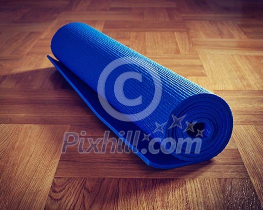 Vintage retro effect filtered hipster style image of Yoga mat on wooden floor Vintage retro effect filtered hipster style image of Yoga mat on wooden floor